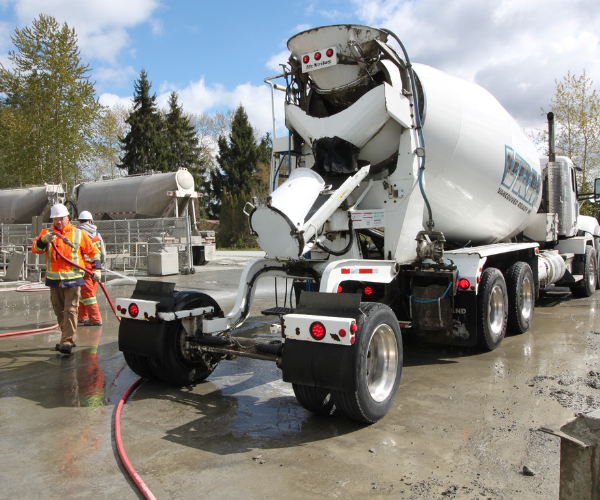 Workers guiding concrete pour from VRM truck on site – concrete suppliers Surrey in action.