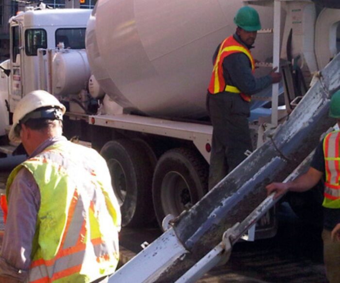 Concrete crew placing controlled density fill from mixer truck in urban project