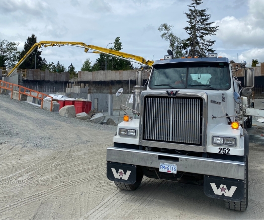 Concrete boom pump truck at Langley job site with active foundation work