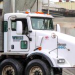 Concrete truck chute vs pump: A white ready-mix concrete mixer truck parked on a construction site.